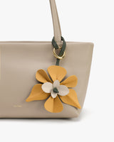 Handbag with a decorative flower accessory attached to the handle.