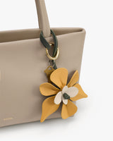Tote bag with large flower keychain attached to handle.