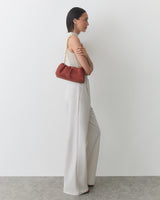 Person in sleeveless top and wide-leg pants holding a shoulder bag