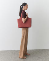 Person holding a large tote bag, standing sideways in casual clothing.