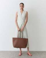 Person wearing a sleeveless dress holding a large tote bag.