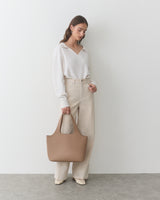 Person posing with tote bag wearing relaxed outfit.