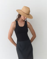 Person wearing a sleeveless top, skirt, and wide-brimmed hat, head tilted downward.