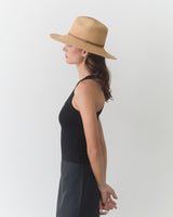 Person in profile wearing a tank top, skirt, and wide-brim hat.