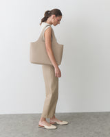 Person wearing sleeveless top with pants, carrying a large shoulder bag.