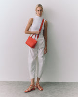Person standing with a small shoulder bag and wearing sandals.