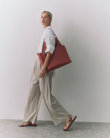 Person walking with large shoulder bag and wearing wide-leg pants and sandals.