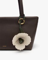 Handbag with floral charm and visible brand logo.