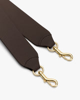 Bag strap with gold clips on white background.