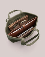 Open tote bag with notebooks, a wallet, and small accessories inside.