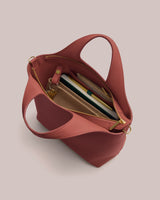 Open handbag with visible items inside, including a notebook and phone.