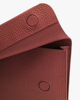 Close-up of a textured handbag flap with snap buttons.