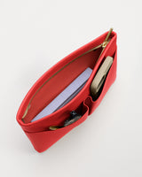 Open bag with a phone, notebook, and pen inside, seen from above.