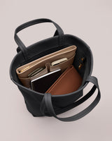 Open tote bag with items like a laptop, notebook, and a pouch inside.