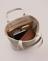 Open tote bag with organized items inside, including a notebook and sunglasses.
