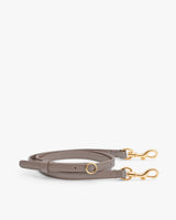 Leather strap with gold clasps laid flat.