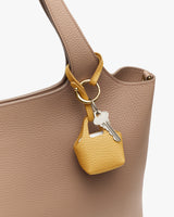 Keychain with small pouch hanging on a textured tote bag handle.
