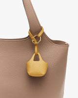 Large bag with small bag charm attached to handle.