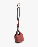 Small textured bag with long strap and gold ring handle.