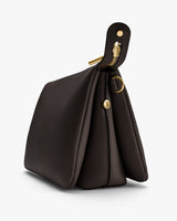 Side view of a structured handbag with gold hardware detailing.
