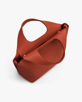 Handbag with a unique looped handle design on a white surface.