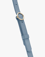 A bag strap with a circular metal buckle.