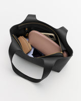 Open tote bag with wallets, glasses, and a phone inside.