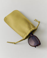 Sunglasses partially inside a soft pouch with drawstrings on a flat surface.