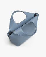 Handbag with a large circular handle and soft, folded design.