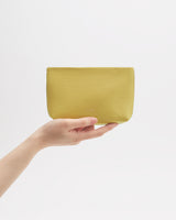 Hand holding a small textured pouch against plain background.