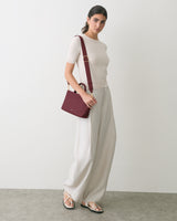 Person standing with shoulder bag and wearing casual outfit with sandals.