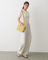 Person in a top and wide pants with a shoulder bag and sandals.