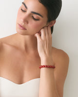 Person touching neck, wearing a bracelet, looking down.