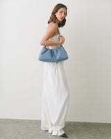 Person in a sleeveless top and long skirt holding a handbag.