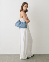 Woman in a long dress holding a chain strap clutch bag.