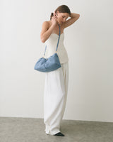 Person holding shoulder bag wearing strapless top and wide-leg pants.