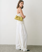 Woman in a white outfit holding a handbag with a chain strap.