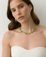Person wearing gold and green jewelry with strapless top