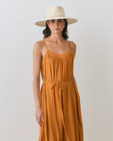 Person wearing a sleeveless dress and wide-brimmed hat.