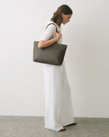 Person holding a large shoulder bag, wearing a sleeveless top and wide-leg pants.