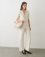 Person wearing a long-sleeve shirt and pants, holding a bag.