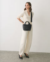 Person in outfit with croc-embossed leather handbag and heels.