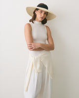 Person wearing a sleeveless top, wide-brim hat, and skirt, with a sweater tied around waist.