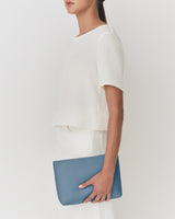 Person holding a clutch bag, wearing a short sleeve top and skirt.