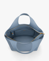 Open handbag with zippered pocket and handles visible.