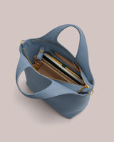 Open handbag with books, a pen, and a zippered pouch inside.