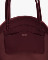 Round handbag with handles and front pocket displaying text.