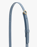 Close-up of a belt with a circular buckle and adjustable holes.