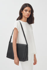 Woman in a top and pants carrying a shoulder bag.