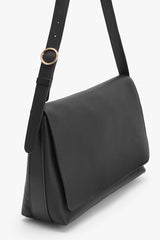 Shoulder bag with adjustable strap and rounded bottom.
